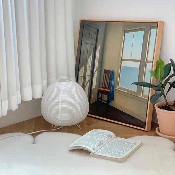 Rijstpapierlamp met drie slanke zwarte metalen pootjes, 21 cm hoog en 23 cm breed, die warm licht verspreidt en past bij Japandi en Wabi Sabi interieurstijl.