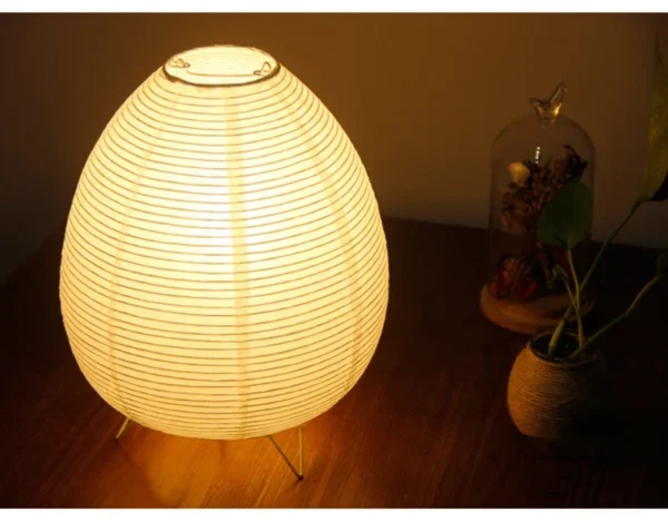 Rijstpapierlamp met drie slanke zwarte metalen pootjes, 21 cm hoog en 23 cm breed, die warm licht verspreidt en past bij Japandi en Wabi Sabi interieurstijl.